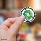 Hand holding a sticker with 'I.N Stray Kids' logo against a blurred background