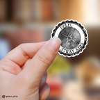 Hand holding a sticker with 'Felix Stray Kids' logo against a blurred background