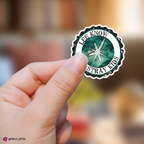 Hand holding a sticker with 'Lee Know Stray Kids' logo against a blurred background
