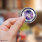 Hand holding a sticker with 'Seungmin Stray Kids' logo against a blurred background