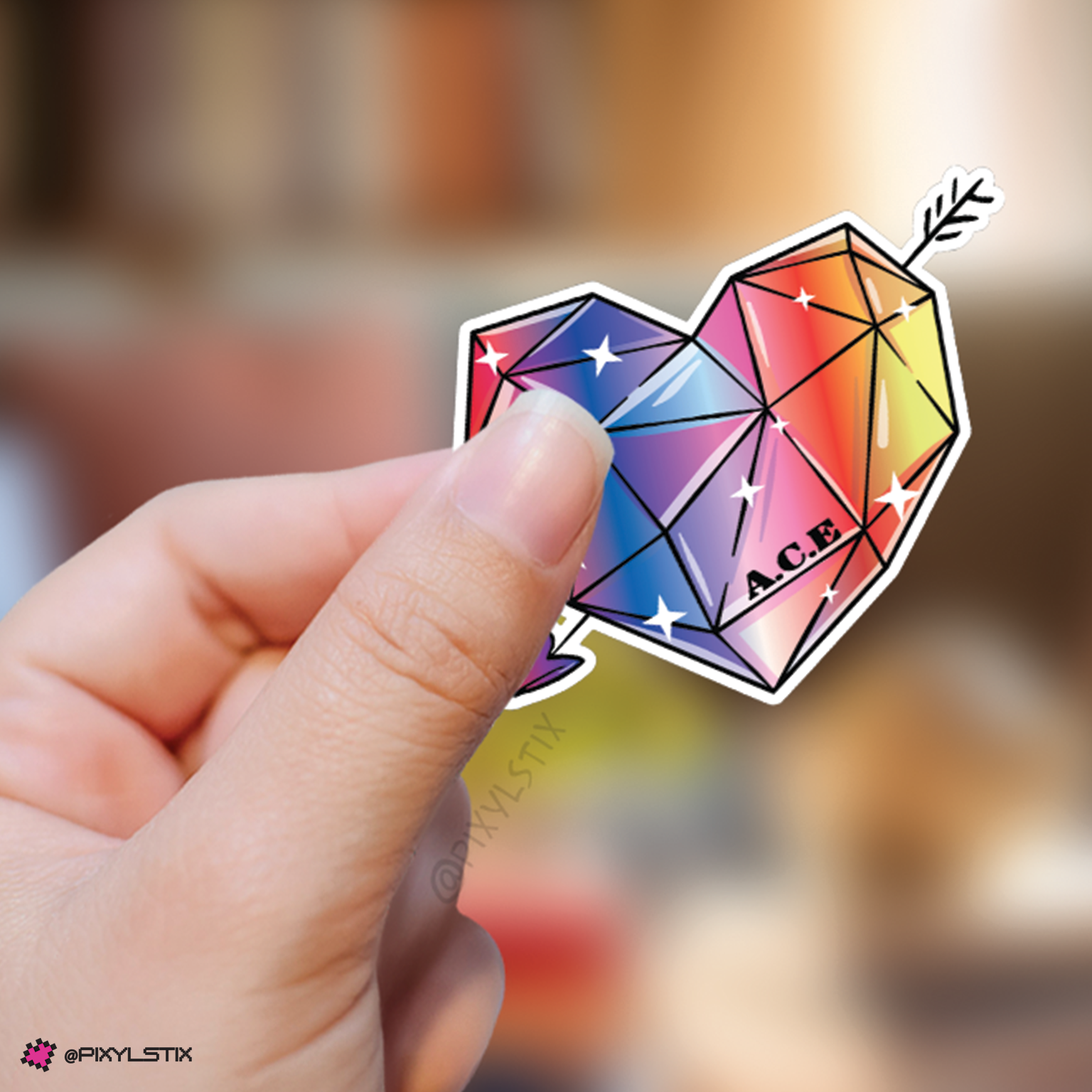 Hand holding a colorful gemstone-shaped sticker with 'A.C.E.' branding against a blurred background.