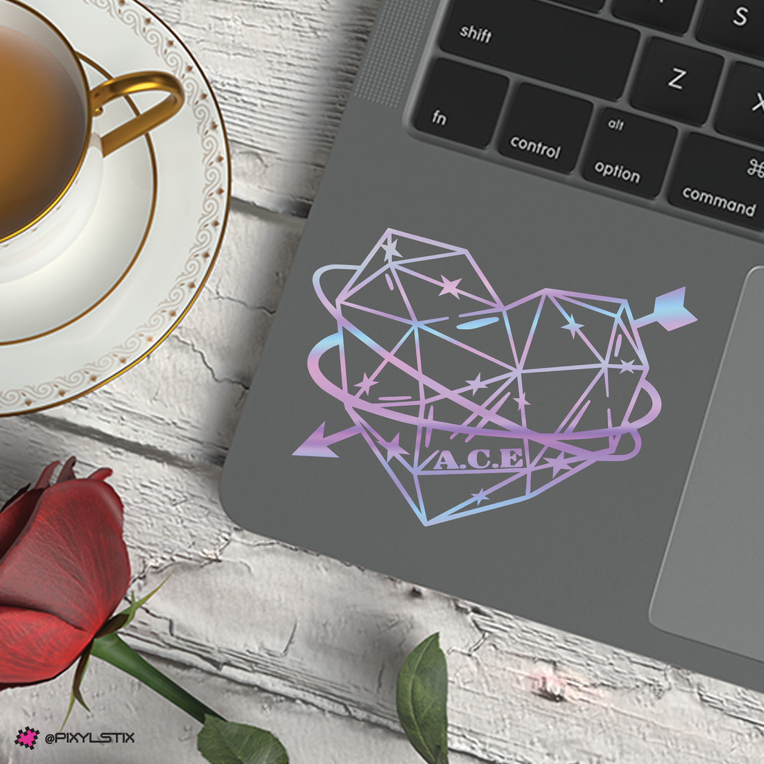 Laptop with geometric heart design on a wooden surface with a cup of tea and rose.