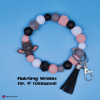 Pink and gray wristlet with bat charm and tassel keychain on a blue background