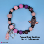 Colorful beaded bracelet with a bat charm and tassel on a blue background
