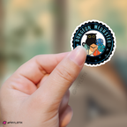 Hand holding a sticker with 'Dungeon Meowster' design against a blurred natural background