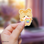Hand holding a hongjoong mighteez sticker with a rainbow heart against a blurred background