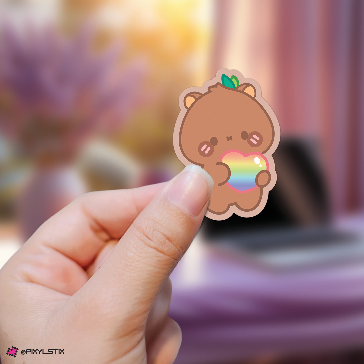 Hand holding a jongho aniteez sticker with a rainbow heart against a blurred background