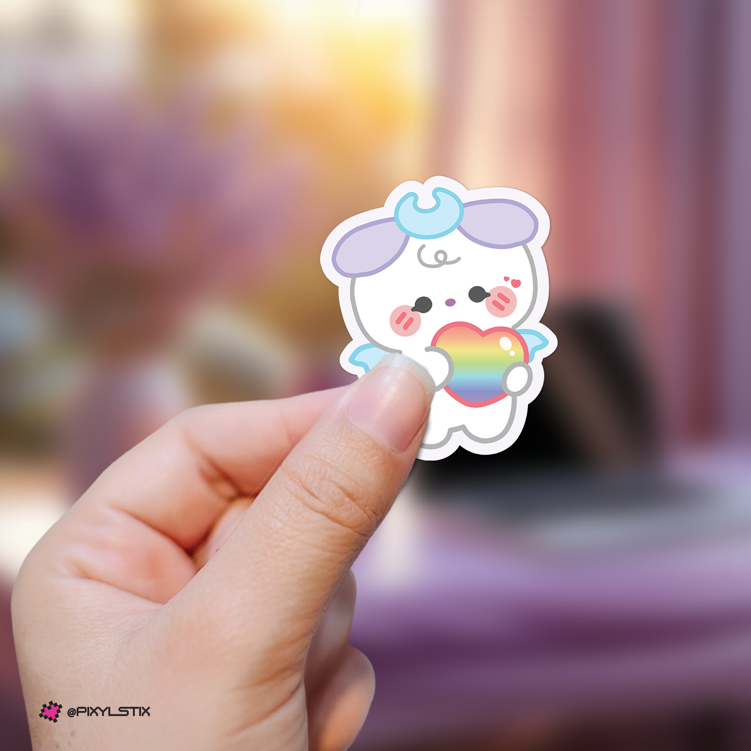 Hand holding a jongho mighteez sticker with a rainbow heart against a blurred background