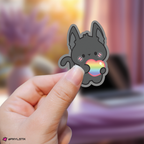 Hand holding a wooyoung aniteez sticker with a rainbow heart against a blurred background