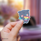 Hand holding a wooyoung mighteez sticker with a rainbow heart against a blurred background