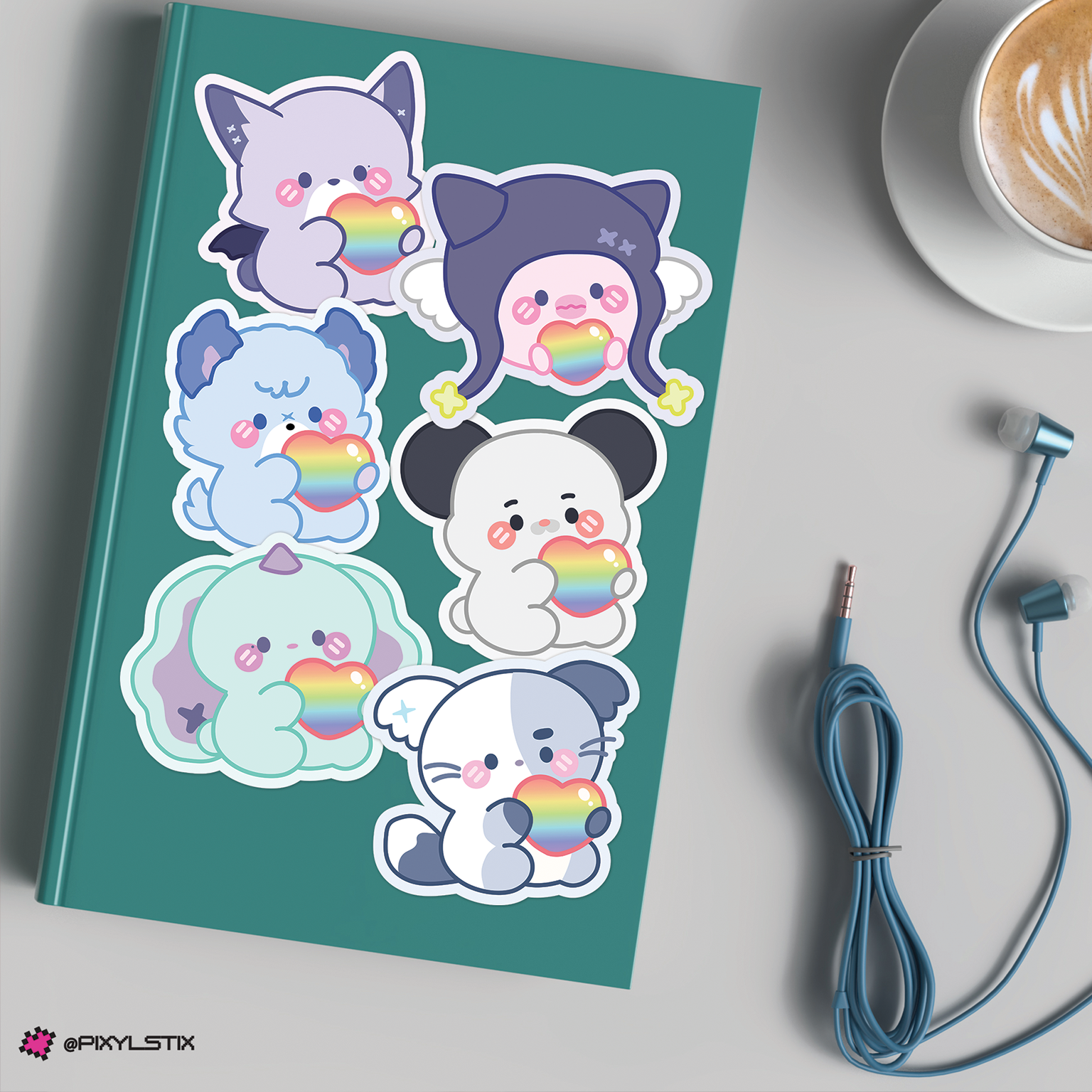 Notebook with xdinary monsters stickers on a table with a cup of coffee and earphones.