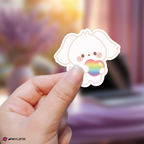 Hand holding a yeosang aniteez sticker with a rainbow heart against a blurred background