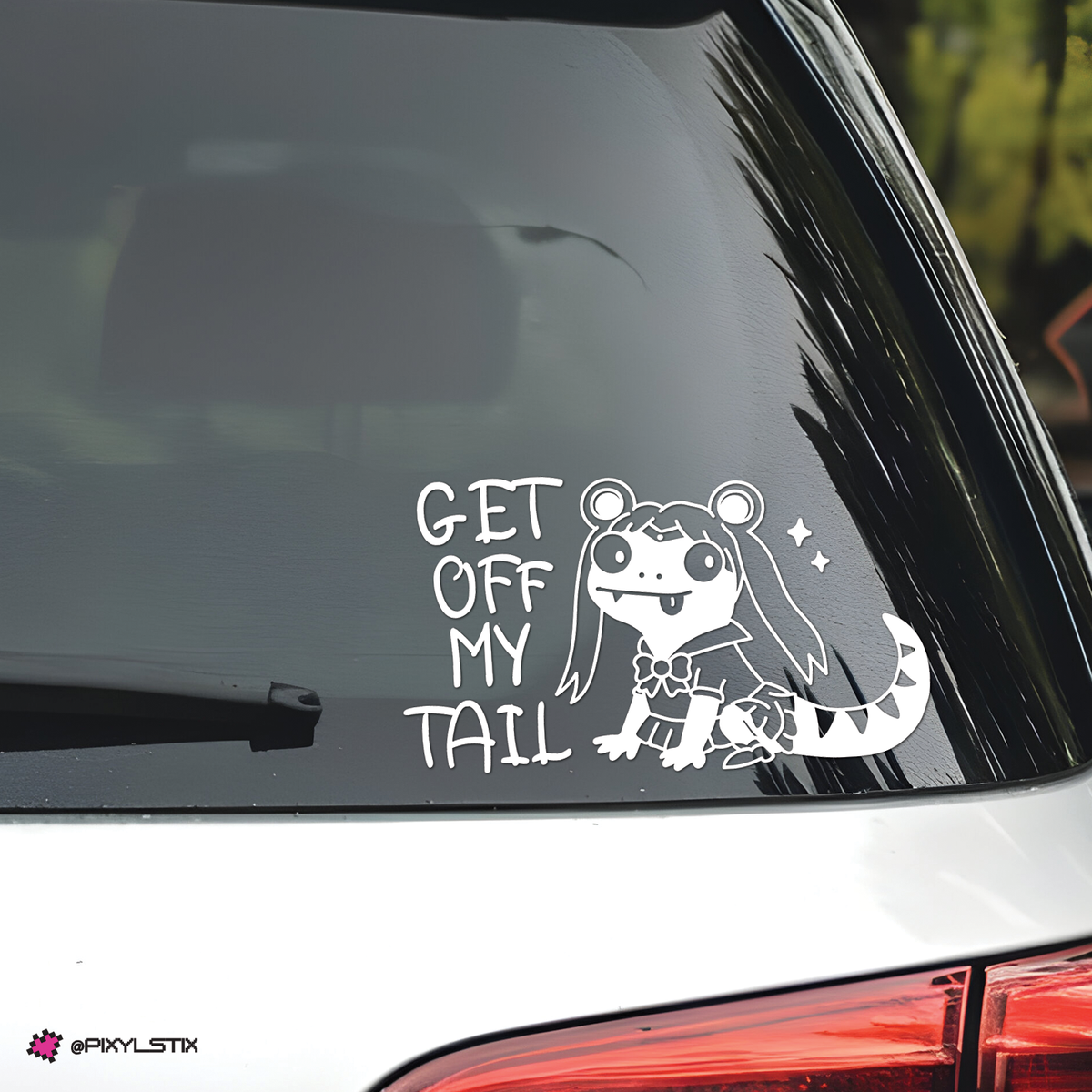 A white vinyl decal applied to the rear window of a white car. The decal features the text 'GET OFF MY TAIL' in a hand-drawn font next to a lizard character with long hair and a striped tail.
