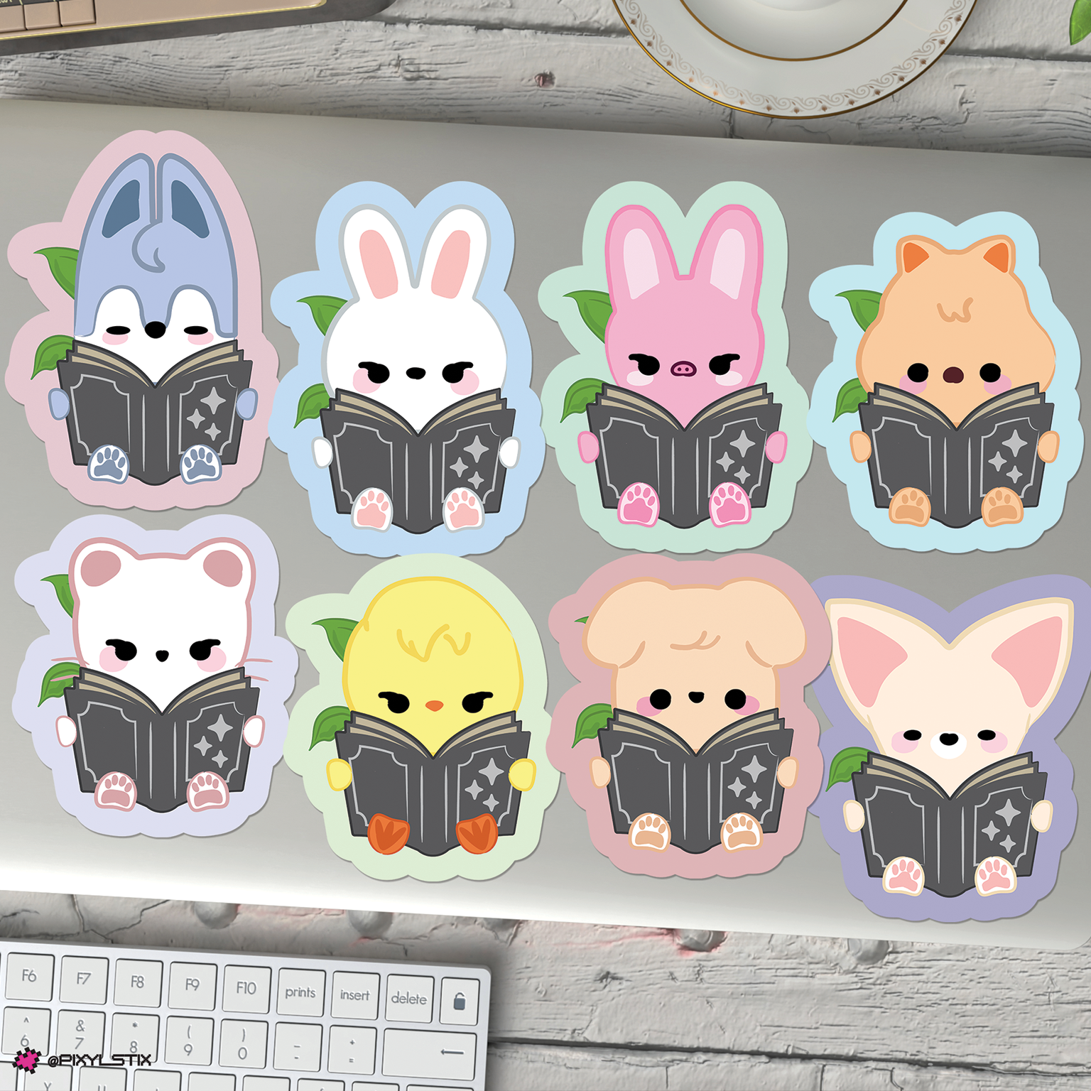 Eight cute skzoo stickers arranged on a laptop lid, each holding a book. 