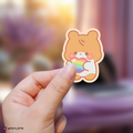 Hand holding a zeroni hanbin sticker with rainbow colors against a blurred background