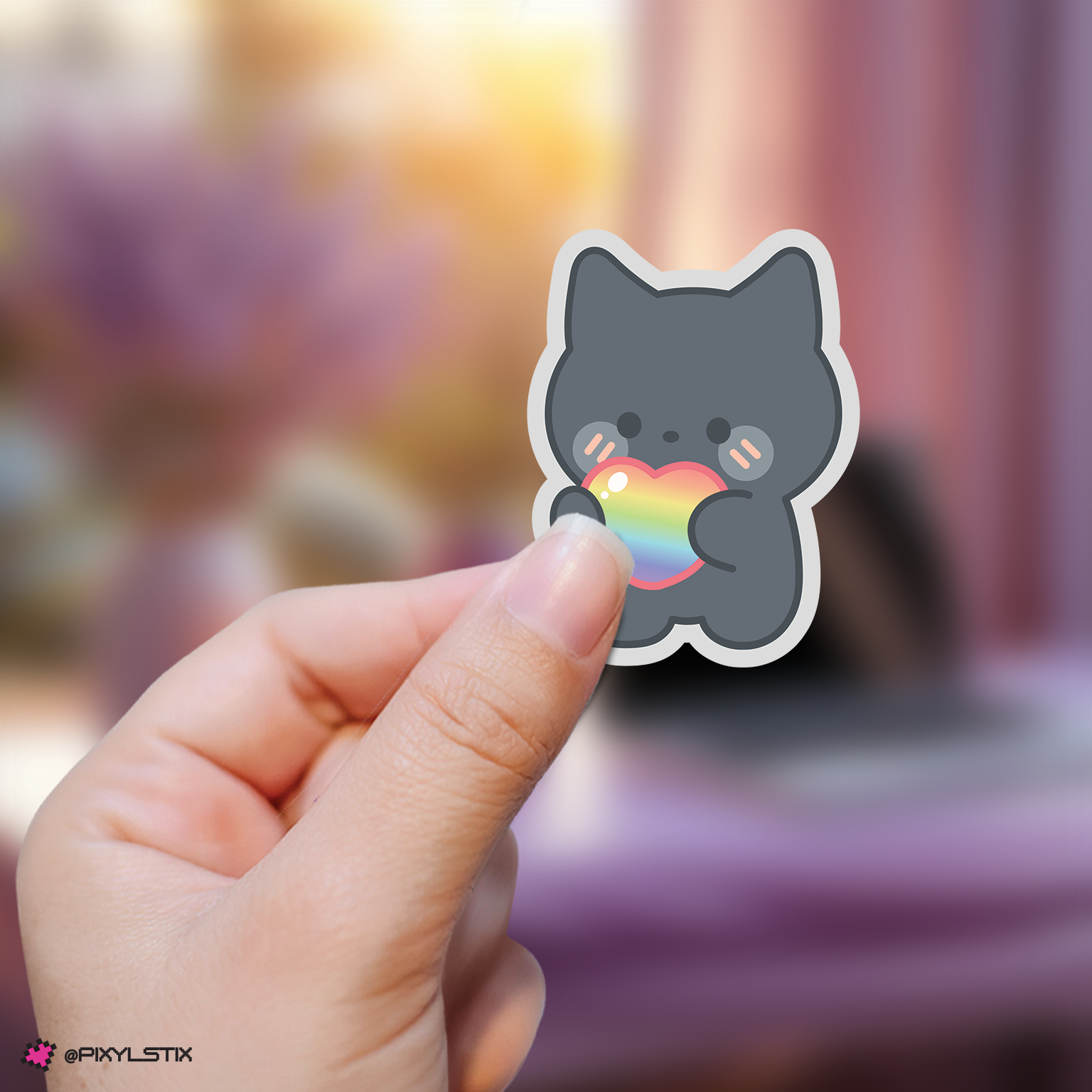 Hand holding a zeroni jiwoong sticker with a rainbow heart against a blurred background