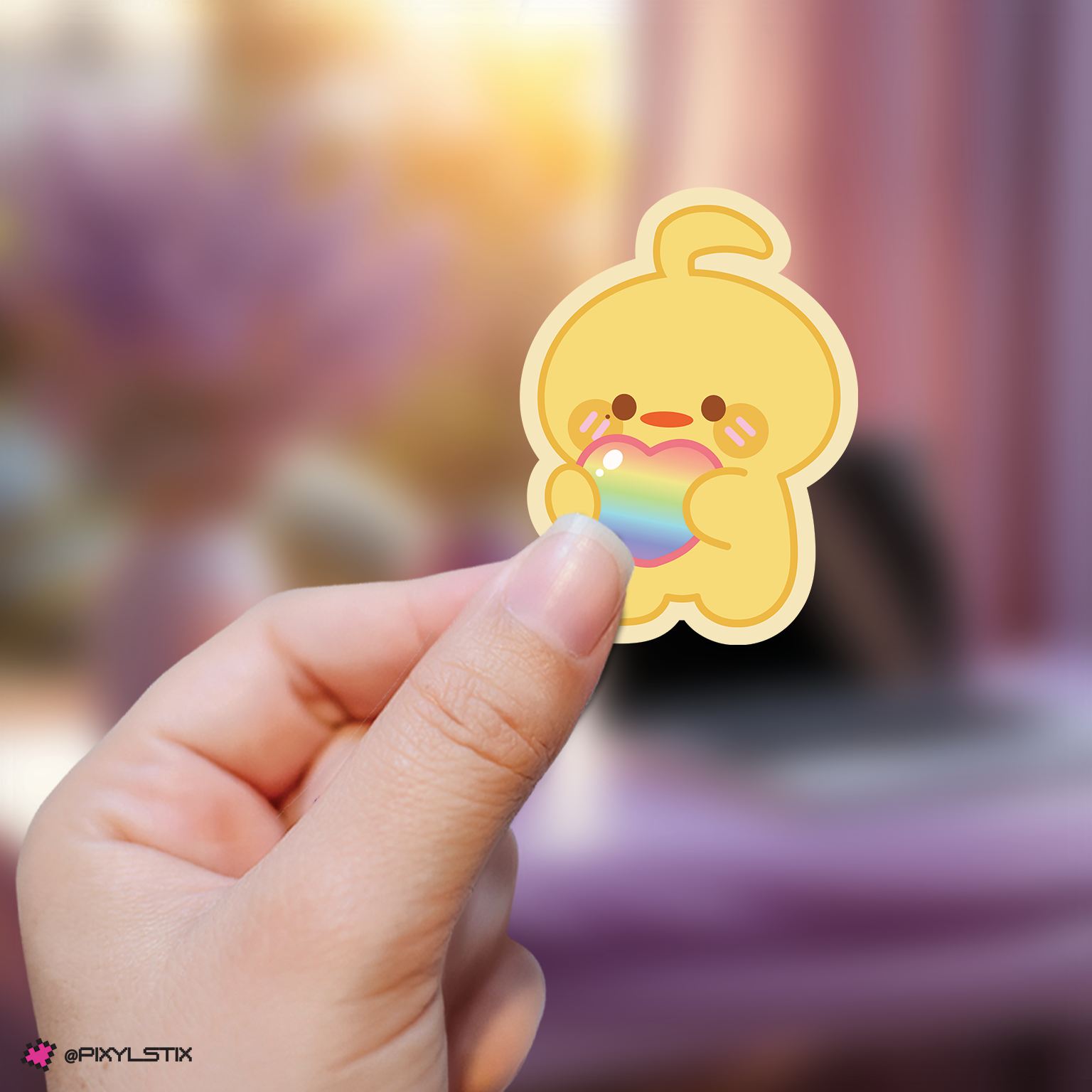 Hand holding azeroni taerae sticker with a rainbow bubble against a blurred background