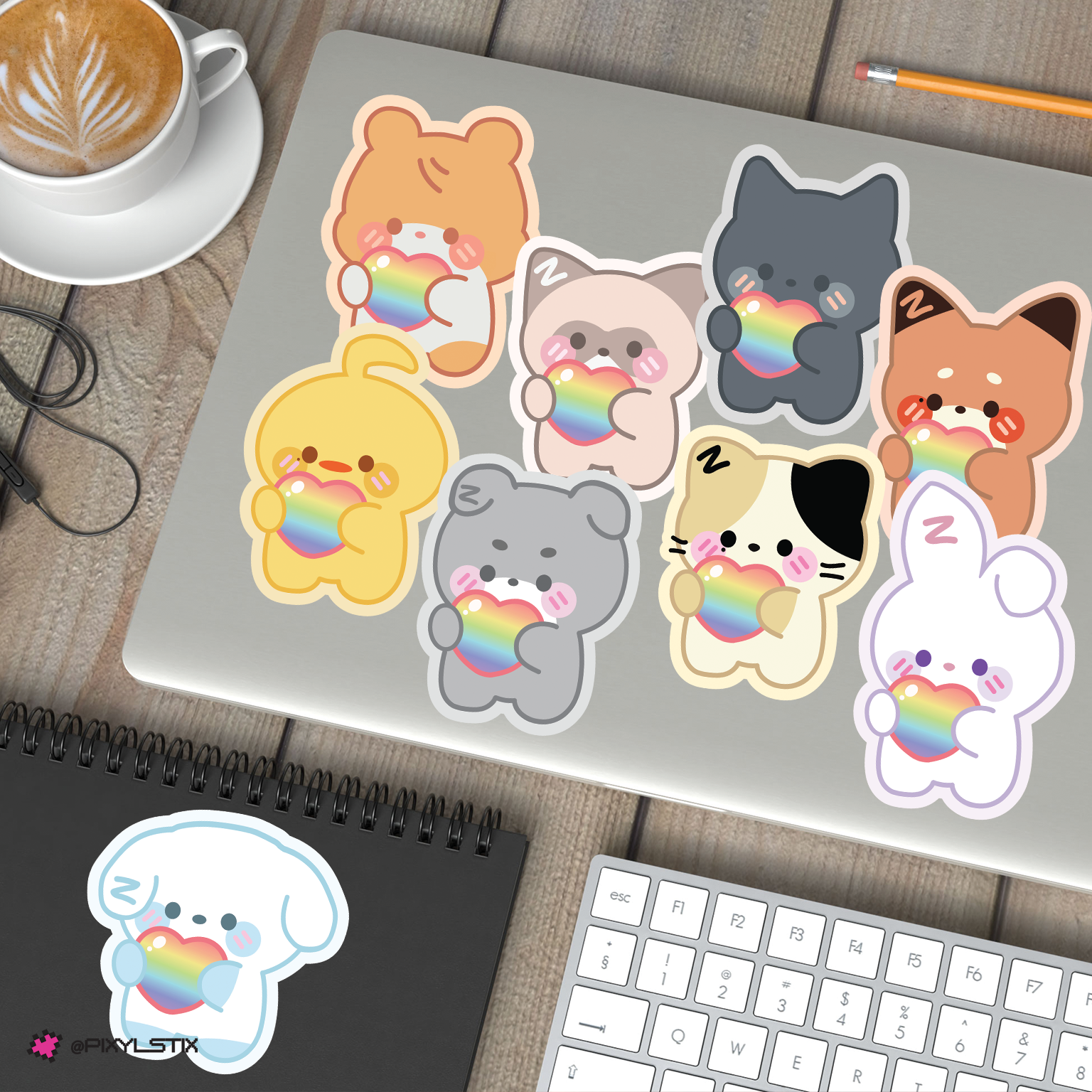 A set of zeroni stickers with rainbow accents displayed on a laptop, notebook, and keyboard on a wooden desk, with a coffee cup in the corner.